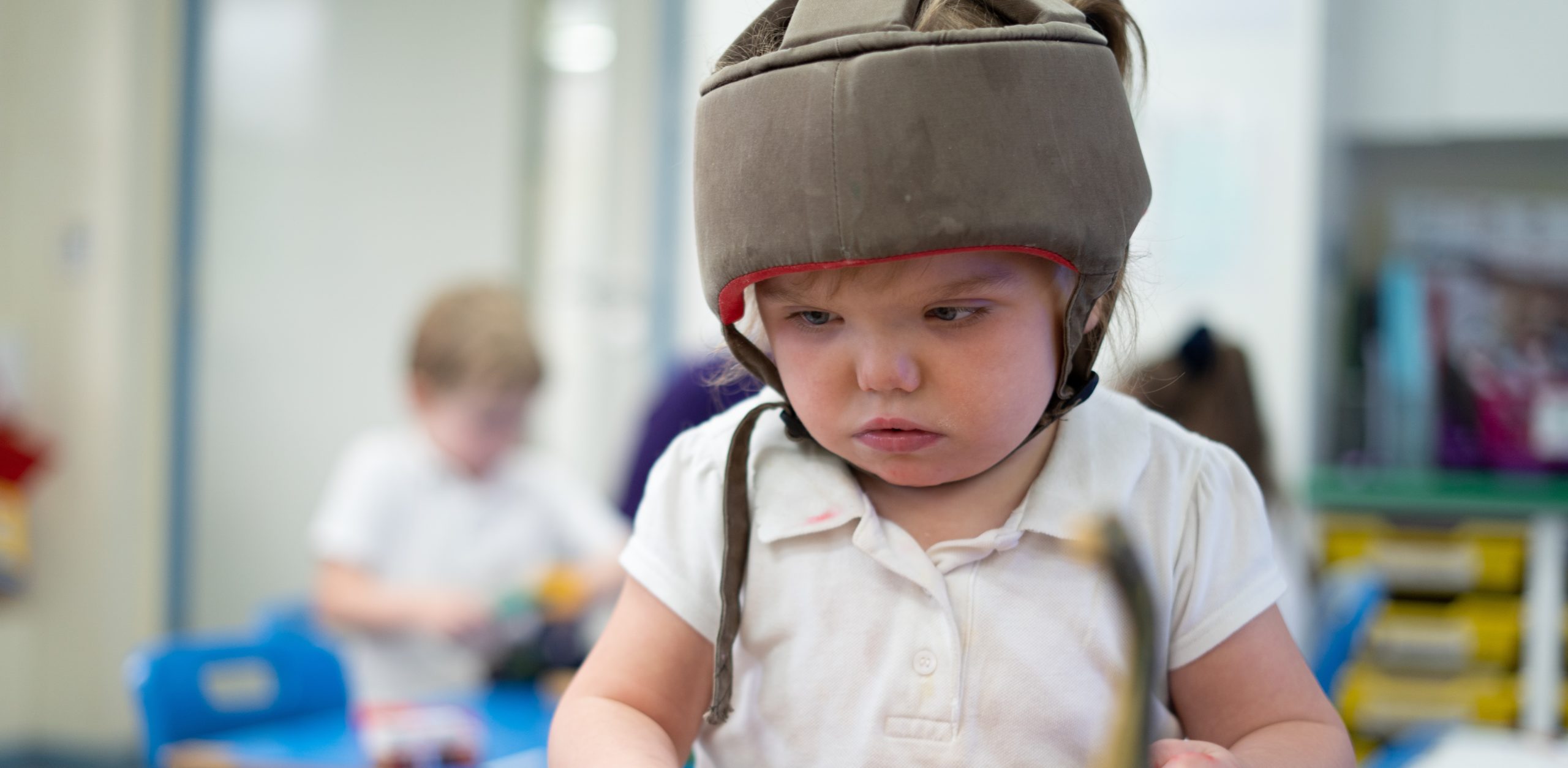 A young girl is pictured sat at her desk in her classroom.