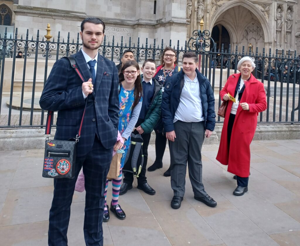 Five students are pictured posing for the camera, alongside their teachers, outside Westminster Abbey during a trip to London to attend the annual Commonwealth Day service.