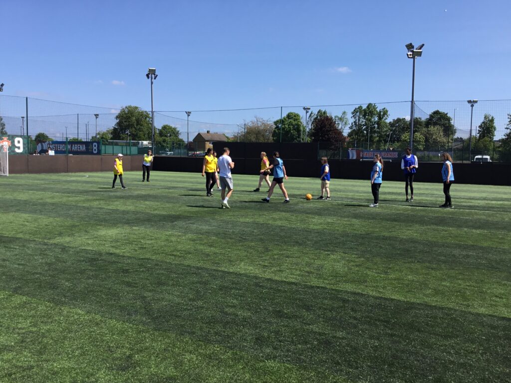 Photo showing a group of students playing a game of Football together on an astro turf on the academy grounds.