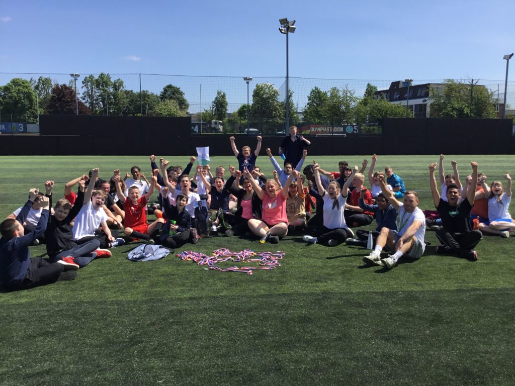 A large group of students are pictured sat on the grass on the academy grounds, after having won several trophies and medals for their Football success.