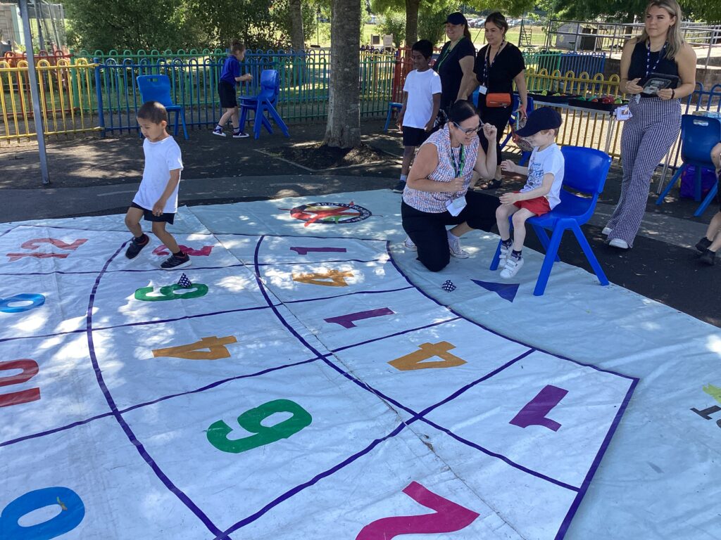 Some young, male pupils are pictured participating in sporting activities, outdoors on the academy grounds. They are being supervised by some members of staff.