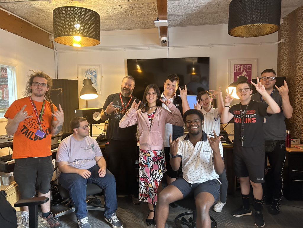 A group of Milestone Academy students are seen smiling for the camera whilst in the recording studio recording vocals for a song they will release.