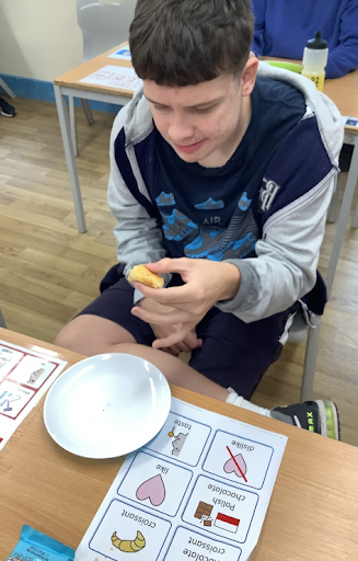 A male student is pictured having a snack during a break from working.