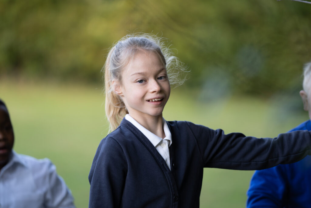 A young girl outside smiling at the camera