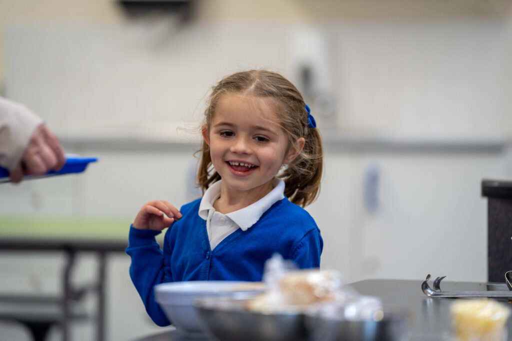 A young girl behind a table smiling