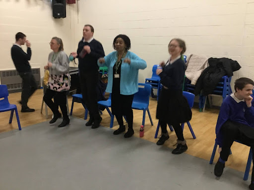 A small group of Milestone Academy pupils are pictured gathered in an activity studio, participating in a sign language session.