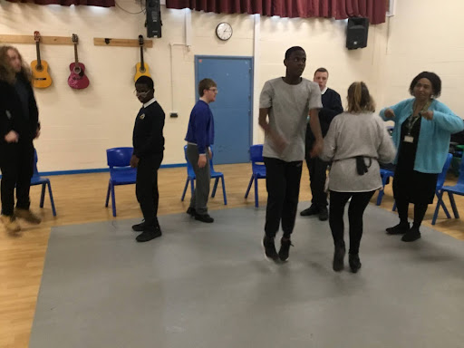 A small group of Milestone Academy pupils are pictured gathered in an activity studio, participating in a sign language session together.