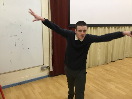 A male student is pictured holding both his arms out, like a bird, during a sign language session in the activity studio.