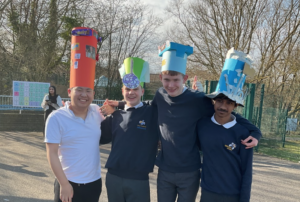 Students stood wearing hats they have made